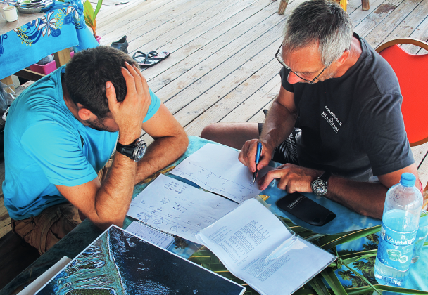 Laurent Ballesta and Jean-Marc Belin studying the parameters of the 24-hour dive. The essential information is written on a slate for the diver and on a board for the surface team.
