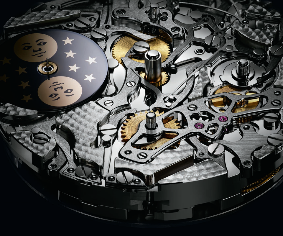 The gleaming finishes of the three key components: the 24 hour wheel (to the right of the moon disk), the central lever running through the center of&nbsp;the movement, and the program wheel to the right of the lever.
